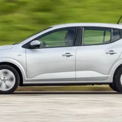 Srebrne auto w ruchu, być może najtańsze auto na świecie, z kierowcą w środku.