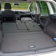 Wnętrze VW Sportsvan z rozłożonymi tylnymi siedzeniami, tworzącymi dużą przestrzeń bagażową. Widoczny schowek i gaśnica.