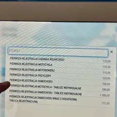 Na ekranie terminala widać listę usług związanych z rejestracją pojazdów. Sprawdzam, ile kosztuje przerejestrowanie samochodu.
