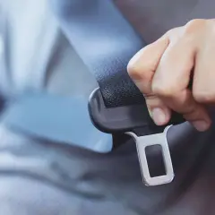 Dłoń zapina pas bezpieczeństwa. Uniknij mandatu za brak pasów, zapnij się!