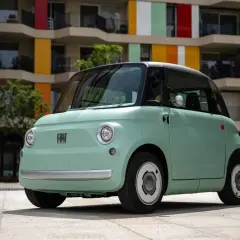 Uroczy, miętowy Fiat Topolino stoi przed kolorowym budynkiem.