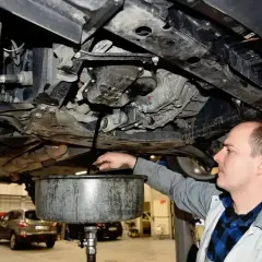 Mechanik spuszcza olej z silnika. Pamiętaj o regularnej wymianie oleju, by silnik służył Ci długo.