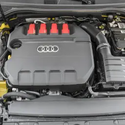 Silnik 2.0 TFSI z czerwonymi elementami i logo Audi. Widoczny akumulator i zbiornik płynu.