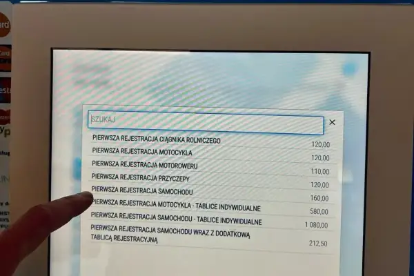 Na ekranie terminala widać listę usług związanych z rejestracją pojazdów. Sprawdzam, ile kosztuje przerejestrowanie samochodu.