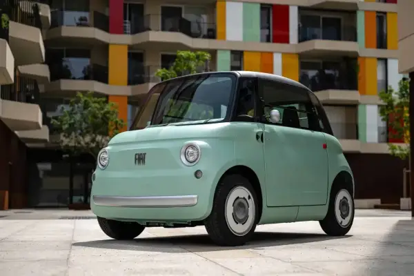 Uroczy, miętowy Fiat Topolino stoi przed kolorowym budynkiem.