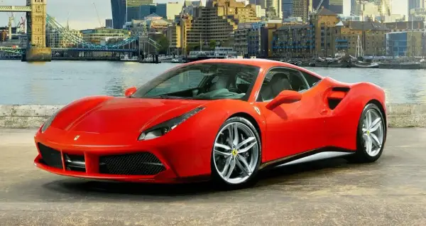 Czerwone Ferrari 488 GTB z dumą prezentuje się na tle Londynu, z Tower Bridge w tle.