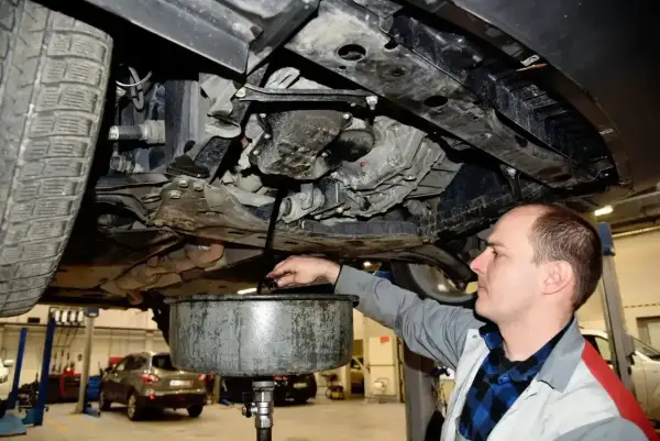 Mechanik spuszcza olej z silnika. Pamiętaj o regularnej wymianie oleju, by silnik służył Ci długo.