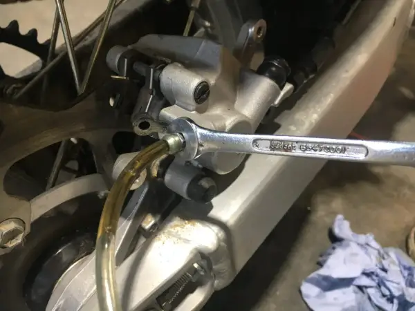 Klucz nasadowy odkręca odpowietrznik podczas wymiany płynu hamulcowego w motocyklu.