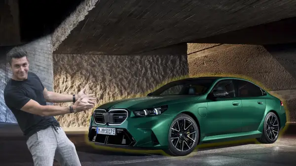 Mężczyzna z entuzjazmem prezentuje lśniące, zielone bmw g90 pod betonowym zadaszeniem.