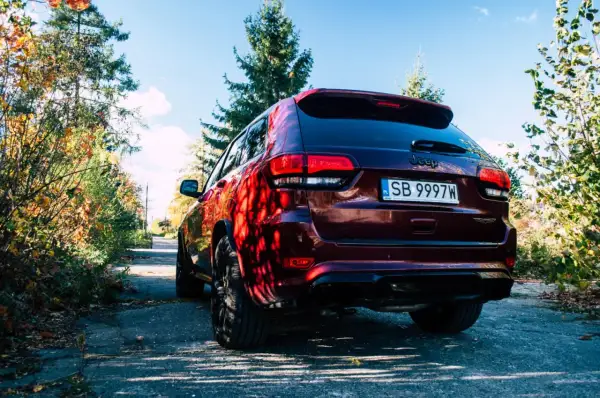 Ciemnoczerwony Jeep Grand Cherokee Trackhawk na tle jesiennego krajobrazu.
